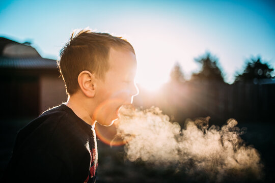 Playful boy blowing breath in winter air