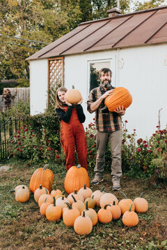 Father and daughter work together to move pumpkins in backyard