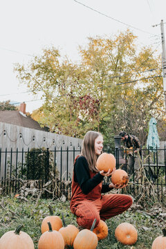 Father and daughter work together harvesting pumpkins in yard