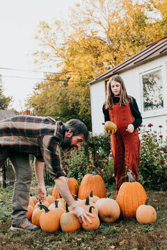 Father and daughter work together to gather harvested pumpkins