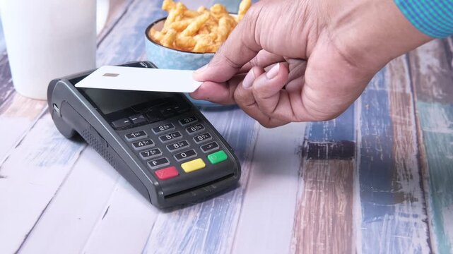 Contactless payment transaction with credit card and pos terminal on wooden table