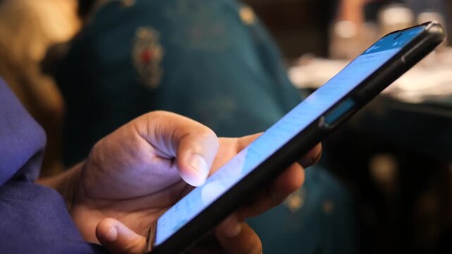 Person using smartphone, scrolling through messages on screen with finger motion