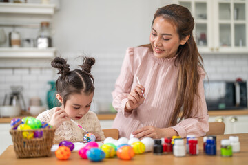Asian mother and little daughter painting colorful easter eggs with brush at kitchen, Happy family spring holiday celebration, childhood creative art craft learning, motherhood childcare, easter day
