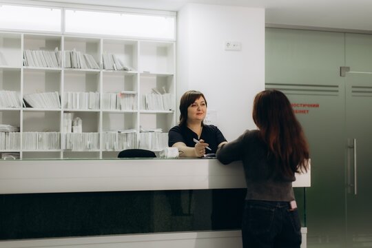 Medical receptionist checking in patient at clinic desk