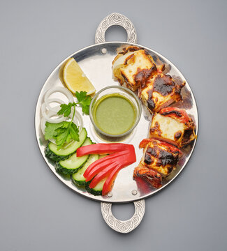 Delicious platter with grilled food and fresh vegetables served in a round metal dish