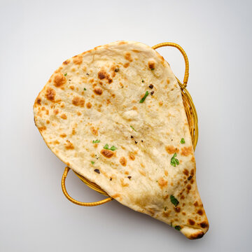 Freshly baked naan bread served in a basket on a plain background