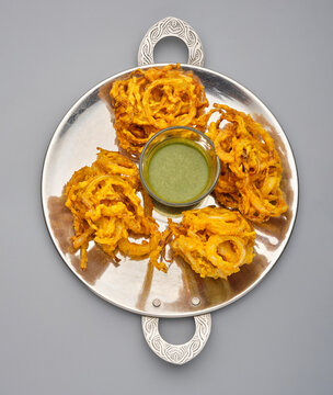 Crispy onion rings served on a tray with green chutney at a food festival in the afternoon