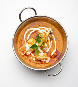Delicious curry dish with rice, yogurt, and herbs served in a metal bowl during lunchtime at a restaurant