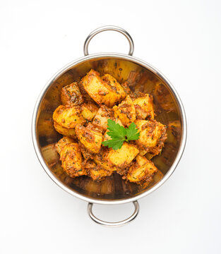 Delicious dish of spiced potatoes served in a metal bowl on a white background