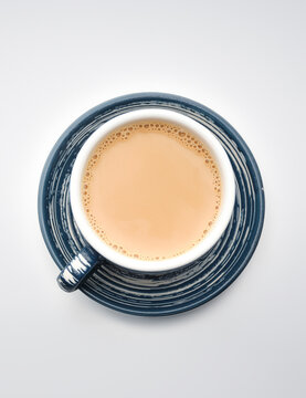 Hot beverage in a cup placed on a round blue saucer with a white background during morning or afternoon time