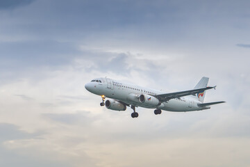 Obraz premium Phuket Thailand 25 11 2025: The Airbus A320-232 aircraft of the Thai airline Bangkok Airways flies with the landing gear extended against the background of the colorful sky.
