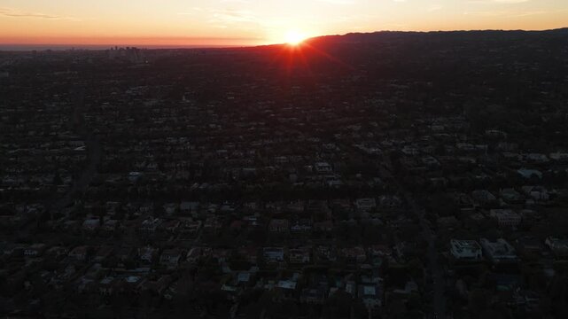 Aerial wide tilting-up shot of The Flats neighborhood in Beverly Hills during sunset in Southern California. 4K