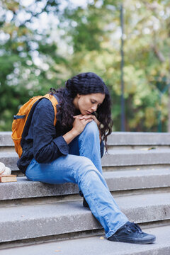 Young student feeling sad and sitting alone on stairs