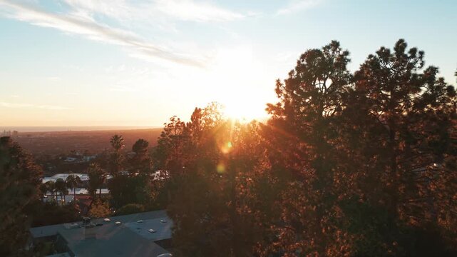Low rising aerial shot of homes in Beverly Hills with sun flare in Southern California. 4K