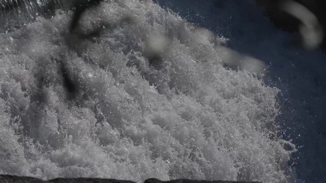 Strong waterfall flow splashing over rocks with white foam