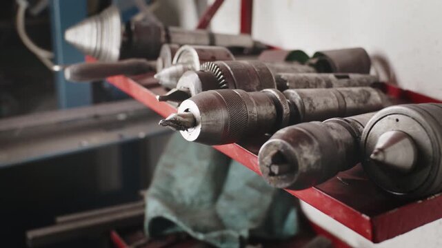 Close-up shot of a steel lathe centers and a drill chuck on a red metal shelf in a machine shop