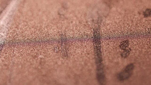 Rotating close-up of detailed dark golden paint specialized sandy texture and radiant glitter particles on surface