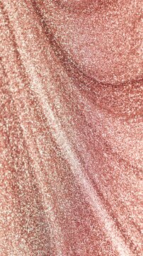 Vertical video of detailed rotating close-up of rose gold paint specialized sandy texture and radiant glitter particles on surface