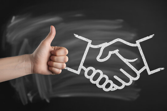 A hand reaching for a chalk drawn handshake on a dark chalkboard background.