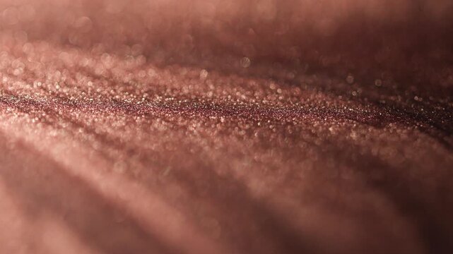 Detailed rotating shot of rose gold paint specialized sandy texture and radiant glitter particles on surface