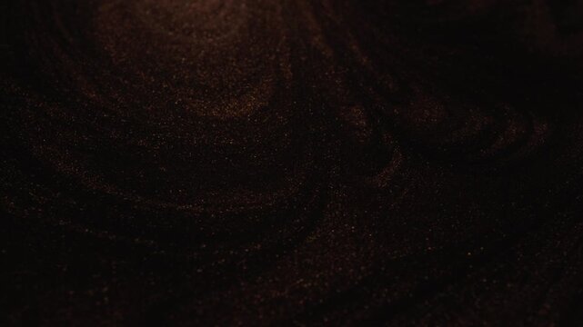 Detailed rotating view of dark rose gold paint with specialized sandy texture and radiant glitter particles flowing and sweeping dynamically on black background