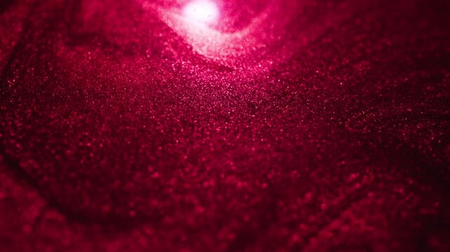 Mesmerizing macro view of dark rose gold paint under red light with sandy texture flowing and swirling slowly while reflecting light on abstract background