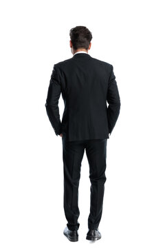 Back view of elegant man standing with hands in pockets