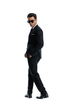 Fashion man walking with hands in pockets wearing sunglasses