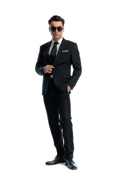 Elegant man wearing sunglasses and adjusting suit