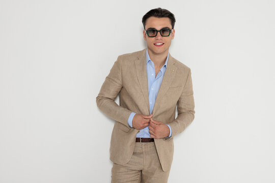 Stylish man adjusting jacket and smiling while preparing