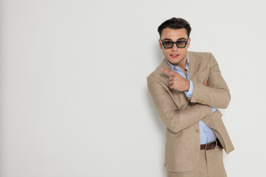 Cool man pointing finger to side with crossed arms
