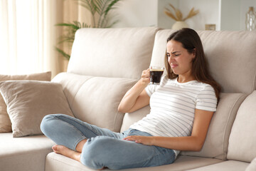 Obraz premium Woman tasting bad coffee on a couch at home