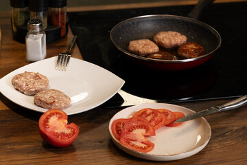 Traditional Balkan grilled minced meat dishes, kebapcheta and meatballs, being cooked in a frying pan in a home kitchen