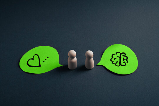 Rational versus emotional communication concept with wooden figures and heart and brain speech bubbles
