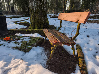 old wooden bench in graveyard. Snow covered burial ground.