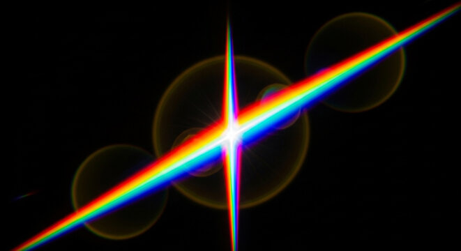 Vibrant rainbow light beam with lens flares on a black background creating a colorful spectrum effect