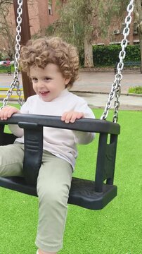 Ni&ntilde;o jugando seguro en columpio cerrado elevado en parque infantil moderno