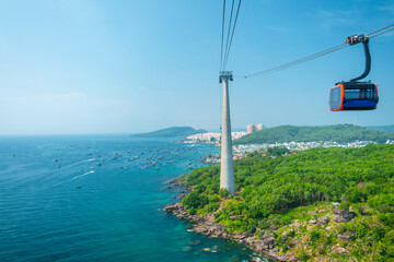 Cable car cabin traveling over turquoise sea and lush green hills in Phu Quoc island, Vietnam. Cable car support tower with gondola above tropical ocean. Modern tourism technology and infrastructure © samael334