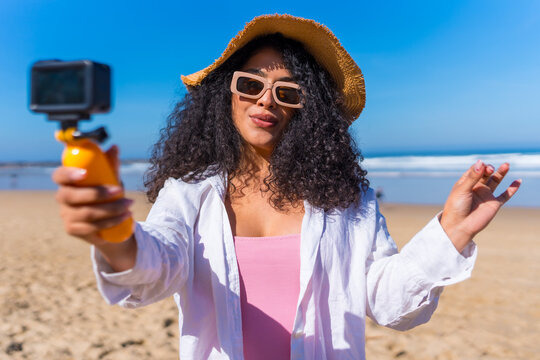 Young woman vlogging travel experiences on sandy beach