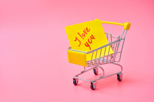 Shopping cart with yellow I love you note on pink background