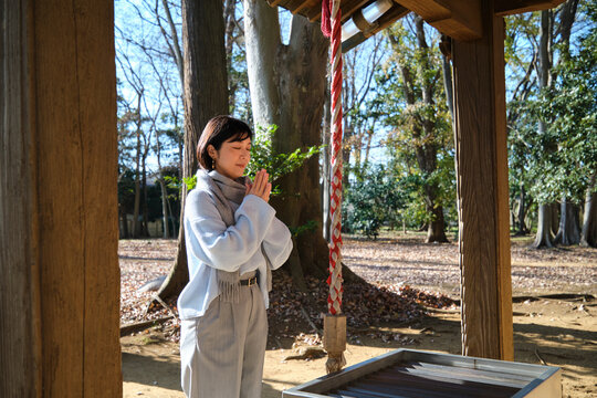 Woman praying at outdoor shrine in morning sunlight