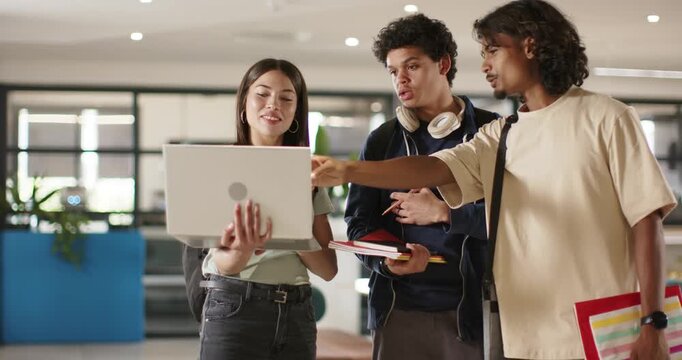 Diverse students working in study area woman showing laptop men with notes pointing reviewing work
