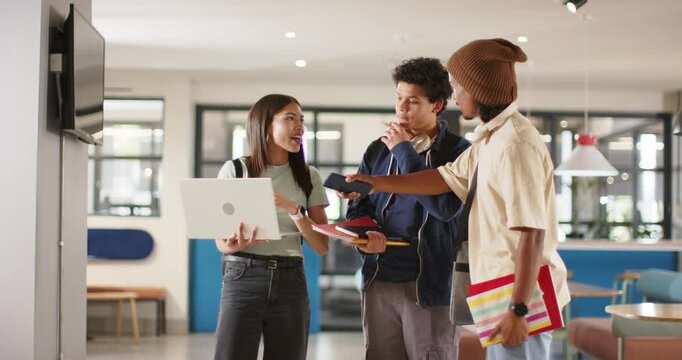 Diverse students in lounge after laptop cue, sharing and pointing at wall display for project