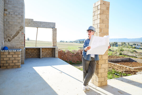 Architect reviewing building plans at construction site outdoors