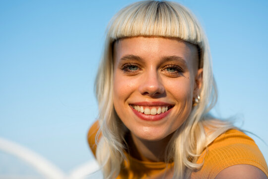 Smiling hipster with blonde hair outdoors looking at camera urban lifestyle