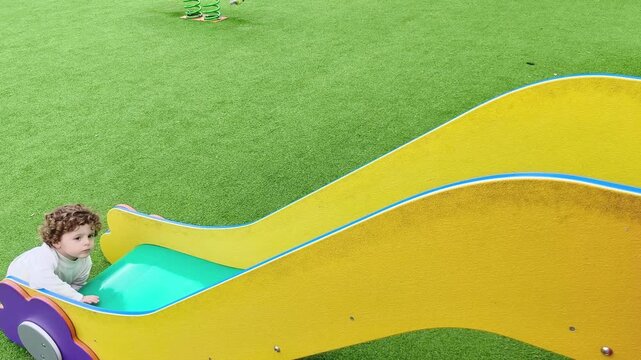 Ni&ntilde;o jugando solo en tobog&aacute;n de parque infantil moderno y seguro
