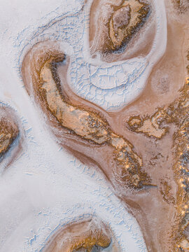 Aerial view of swirling white salt plains meeting textured ochre earth in an abstract dance of nature's artistry, Lake Campion Nature Reserve, Western Australia, Australia.