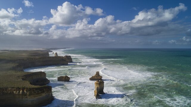 Aerial view of the dramatic cliffs and stacks of the Twelve Apostles meet the turquoise waters under a vast sky, Port Campbell, Victoria, Australia.