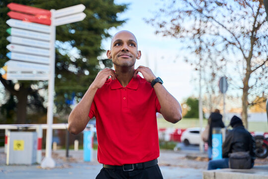 Confident man in red shirt expressing positivity outdoors in urban setting
