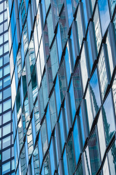 Modern blue glass facade with reflective windows and grid lines creating abstract architectural pattern on urban corporate building